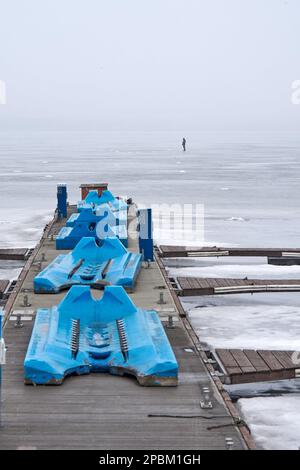 Pier und einsamer Fischer auf dem dünnen Quelleis des Voronesch-Reservoirs. Jedes Jahr nehmen verzweifelte Liebhaber des Winterfischens das Eis des Voronesch-Reservoirs. Die Fischer werden nicht durch ein Auftauen oder sogar das Eintreffen des Frühlings aufgehalten. Die Aufregung treibt diese Menschen auf dünnem und manchmal verschwommenem Eis an, was zu Spannungen für den Dienst der Stadt führt. Rettungskräfte und Polizisten entfernen Fischer aus Eisschollen und fischen sie aus Gully, während medizinische Arbeiter um das Leben von Menschen kämpfen, die ertrinken oder kalt sind. (Foto: Mihail Tokmakov/SOPA Images/Sipa USA) Stockfoto