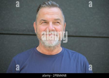 Fröhliches, lebhaftes, bärtiges Männerkopf- und Schulterporträt mit einem Lächeln zur Seite Stockfoto