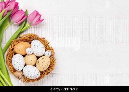 Rosa Tulpenblüten Bouquet und ostereier. Auf einem weißen Holztisch. Flach verlegt Stockfoto