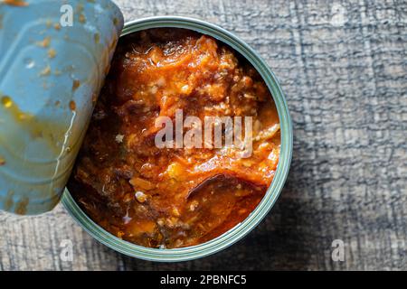 Offene Sardinen in Tomatensoße auf Holzhintergrund, aus nächster Nähe, Draufsicht Stockfoto