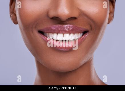 Luziöse Lippen. Eine junge Frau redet vor einem lila Hintergrund. Stockfoto