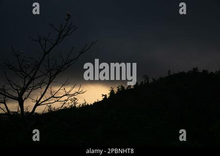 Die Morgensonne geht von der anderen Seite des Berges auf. Die Sonne ist von Wolken bedeckt. Foto aus Chittagong, Bandarban, Bangladesch. Stockfoto