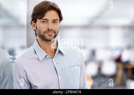 HES ein selbstbewusster junger Geschäftsmann. Porträt eines hübschen jungen Geschäftsmannes, der in seinem Büro steht. Stockfoto