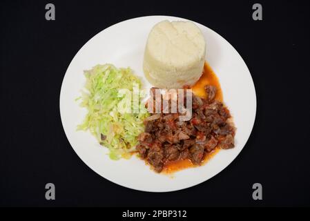 Rindereintopf mit afrikanischem Ugali und gebratenem Kohl Stockfoto