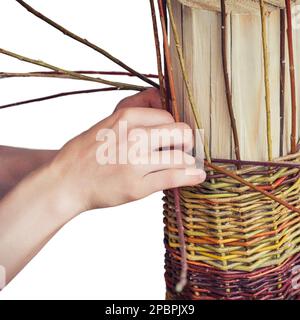 Männer weben einen Korb aus Baumzweigen, isoliert auf weißem Hintergrund. Alte Handwerkskorbmacher-Vintage-Werke. Stockfoto