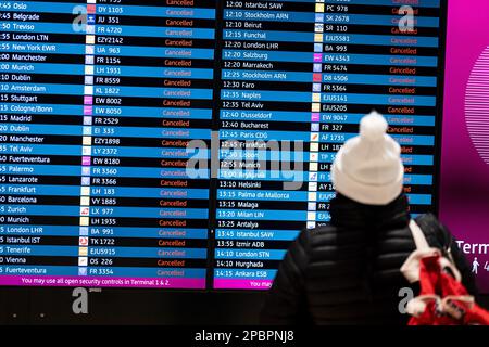 13. März 2023, Brandenburg, Schönefeld: Eine Frau steht vor dem Display mit annullierten Flügen während des Warnstreiks von Verdi am Flughafen BER. Am Flughafen Berlin-Brandenburg BER der Hauptstadt wurden etwa 200 Abflüge aufgrund des Warnstreiks des Sicherheitspersonals abgesagt. Nach Angaben des Flughafens sind etwa 27.000 Passagiere betroffen. Foto: Fabian Sommer/dpa Stockfoto