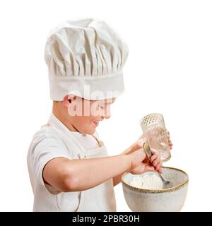 Ein Junge in weißer Koch-Kleidung kocht in einer Küche zu Hause, isoliert auf weißem Hintergrund Stockfoto