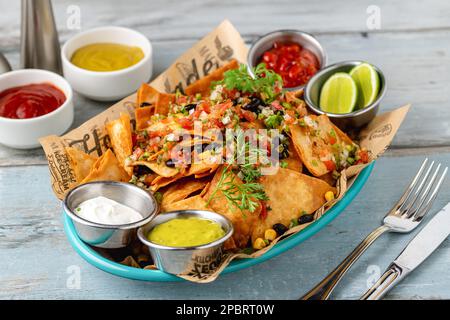 Traditionelle mexikanische Speisen, Nachos mit verschiedenen Saucen auf einem Holztisch Stockfoto