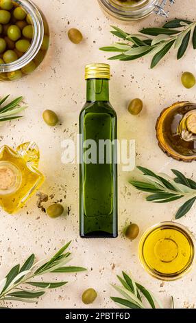 Draufsicht auf eine Glasflasche mit Olivenöl, Blättern und Oliven Stockfoto