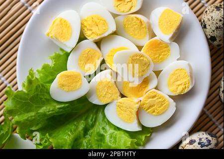 Gekochte Eier Essen, Wachteleier auf weißem Teller, Frühstückseier mit frischen Wachteleiern und Gemüsesalat auf Holztisch Hintergrund - Top Aussicht Stockfoto