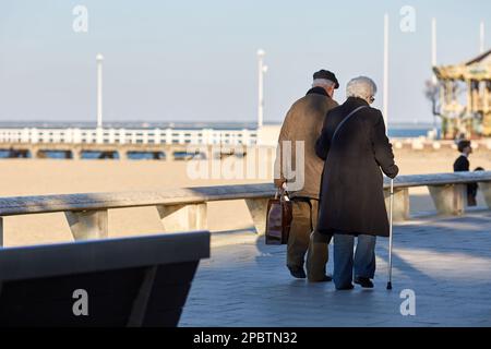 Ein älteres Paar, das an der Strandpromenade entlang spaziert Stockfoto