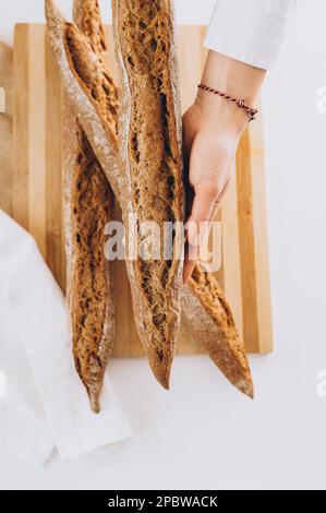 Ein Mädchen hält ein französisches Baguette auf einem Holzbrett Stockfoto