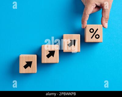 Finanzwachstum, Zinserhöhungen, Inflation, Verkaufspreise und Steuererhöhungen. Mit der Hand werden Holzwürfel mit dem Prozentsymbol angeordnet. Stockfoto