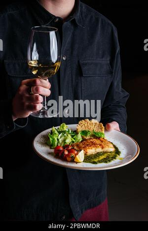 Ein Mann hält einen Teller mit gegrilltem Fisch Stockfoto