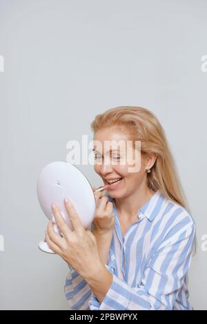 Wunderschöne, reife, ältere Frau, die sich schminkt Stockfoto