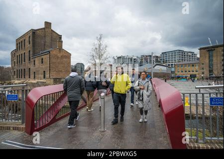 Menschen überqueren die Esperance Bridge über den Regents Canal, Granary Square und Coal Drops Yard, Kings Cross, London, England, Großbritannien Stockfoto