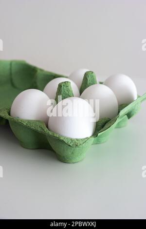 Frische rohe weiße Eier in einer grünen Pappschachtel. Nahaufnahme Studio, isoliert auf Weiß, keine Leute. Stockfoto