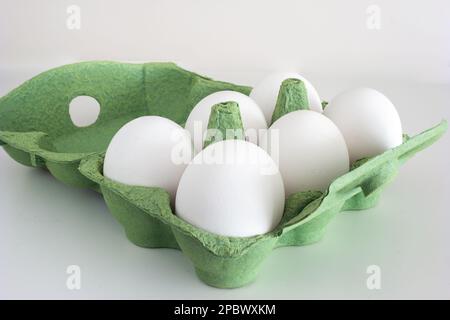 Frische rohe weiße Eier in einer grünen Pappschachtel. Nahaufnahme Studio, isoliert auf Weiß, keine Leute. Stockfoto