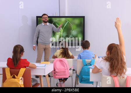 Lehrer, der Schülern Unterricht in der Nähe des interaktiven Brettes im Klassenzimmer gibt Stockfoto