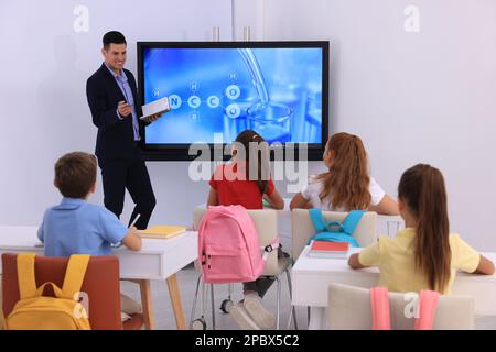 Lehrer, der Schülern Unterricht in der Nähe des interaktiven Brettes im Klassenzimmer gibt Stockfoto