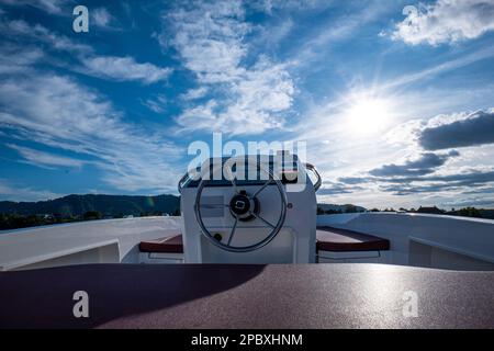 Rundes Metalllenkrad eines kleinen elektrischen Mietboots. Sonniger Sommertag, keine Menschen. Stockfoto