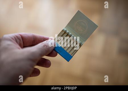 Geöffnete alte alte Schachtel mit unverbrannten Streichhölzern, die von einem männlichen Weißen gehalten wurden. Nahaufnahme, geringe Schärfentiefe, kein Gesicht. Stockfoto