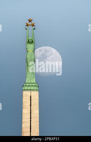 RIGA, LETTLAND - 0ctober 28, 2012: Rigas Freiheitsdenkmal dominiert die Skyline der Stadt bei Mondaufgang. Stockfoto