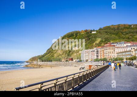 Leute, die an der Promenade am Strand von Zurriola in San Sebastian, Spanien, spazieren gehen Stockfoto