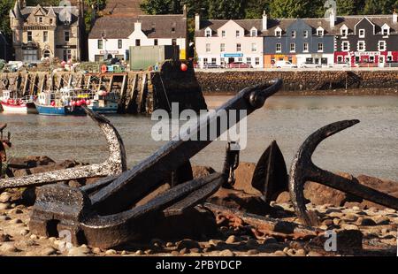 Die farbenfrohen Strandhotels und der Pier in Tobermory, Mull, Schottland mit Anker im Vordergrund und Fischerbooten Stockfoto