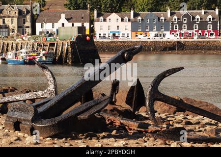 Die farbenfrohen Strandhotels und der Pier in Tobermory, Mull, Schottland mit Anker im Vordergrund und Fischerbooten Stockfoto