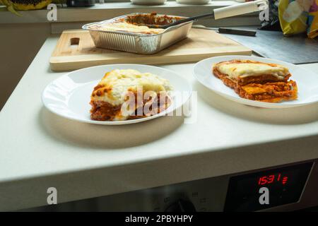 Stücke gebackener frischer Lasagne auf Tellern, Essen vom Markt Stockfoto