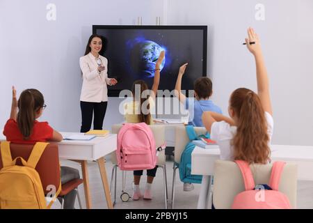 Lehrer, der Schülern Unterricht in der Nähe des interaktiven Brettes im Klassenzimmer gibt Stockfoto