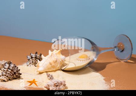 Von oben auf beigefarbenem Tisch mit verschüttetem Sand und verschiedenen Muscheln in der Nähe von Seesternen vor blauem Hintergrund Stockfoto