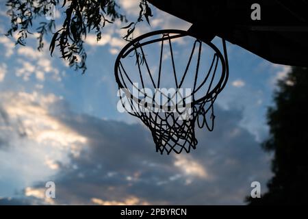 Basketballring oder -Ring in einem Garten. Kleiner Winkel, blauer Sommerhimmel im Hintergrund, keine Menschen. Stockfoto