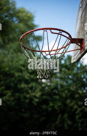 Basketballring oder -Ring in einem Garten. Kleiner Winkel, blauer Sommerhimmel im Hintergrund, keine Menschen Stockfoto