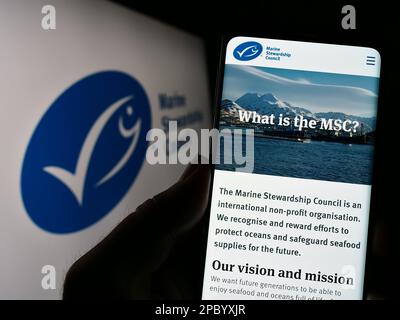 Person, die ein Mobiltelefon mit einer Webseite der Organisation Marine Stewardship Council (MSC) auf dem Bildschirm mit Logo hält. Konzentrieren Sie sich auf die Mitte des Telefondisplays. Stockfoto