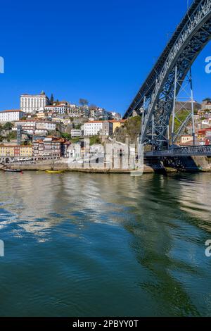 Der wunderschöne alte Hafen von Porto mit der Cais da Ribeira auf der gegenüberliegenden Seite des Flusses Douro. Die eindrucksvolle Bogenbrücke ist die Luis-I-Brücke. Stockfoto