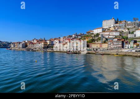 Der wunderschöne alte Hafen von Porto mit der Cais da Ribeira auf der gegenüberliegenden Seite des Flusses Douro. Die eindrucksvolle Bogenbrücke ist die Luis-I-Brücke. Stockfoto