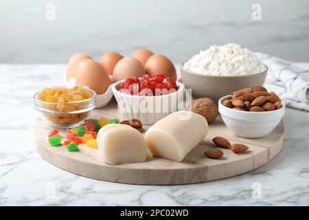Marzipan und andere Zutaten für hausgemachtes Stollen auf einem weißen Marmortisch. Traditionelles deutsches Weihnachtsbrot backen Stockfoto