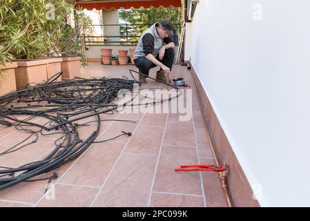Heimgärtnern. Bau eines Mikrobewässerungssystems für Topfpflanzen auf einer Terrasse. Man ersetzt ein altes Tropfbewässerungssystem aus Polyethylen W. Stockfoto