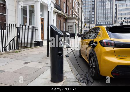 Elektrofahrzeuge, die an einer Straßenladestation am Cavendish Square im Zentrum von London, England, Großbritannien, geparkt sind Stockfoto