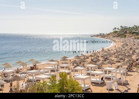 Luxuriöser Strand vor dem Hintergrund der Schönheit des Meeres mit Korallenriffen. Schöner Strand mit Liegen, strohgedeckten Sonnenschirmen und Palmen. Stockfoto