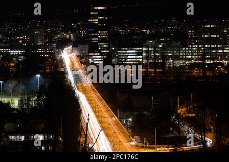 Langzeitwagenverkehr bei Nacht auf der Europabrücke in der Stadt Zürich, Schweiz. Hoher Aussichtspunkt Stockfoto