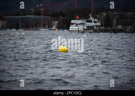 Gelbe Kunststoffboje oder Bojen, die auf einem See in der Schweiz, Europa, schwimmen. Nahaufnahme Teleobjektiv, keine Leute Stockfoto
