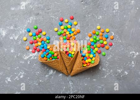Waffelkonus voller traditioneller Süßigkeiten, die auf farbigen Hintergrund fallen, mit Platz für Kopien. Frohes Weihnachtsangebot. Stockfoto