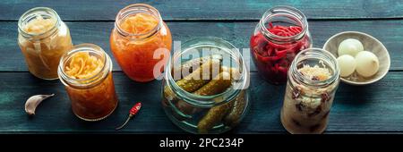 Panorama einer fermentierten Speisevielfalt. Hausgemachte Gemüsekonserven. Sauerkraut, Gurken, Kimchi usw. in Glasgefäßen. Konserven für den Winter Stockfoto