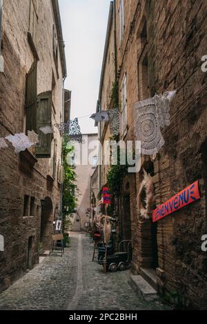 Malerische Straße mit mittelalterlichen Steinfassaden und Geschäften in der Altstadt von Pezenas im Süden Frankreichs (Herault). Stockfoto