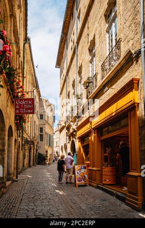 Malerische Geschäfte und Fassaden auf der gepflasterten Straße Rue de la foire in der mittelalterlichen Altstadt Pezenas im Süden Frankreichs (Herault) Stockfoto