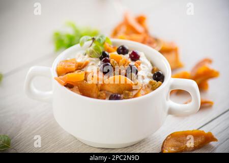 Haferflocken mit kandierten Früchten, Rosinen auf einem Teller auf einem Holztisch. Stockfoto