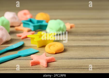 Verschiedene Farben spielen Teig mit Werkzeugen und Formen auf Holztisch, Nahaufnahme. Platz für Text Stockfoto